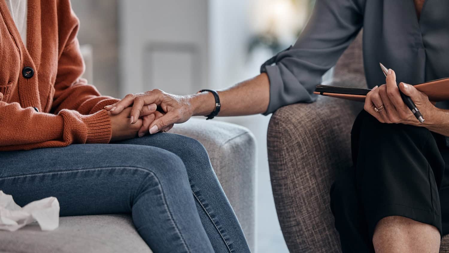 discreet close shot of woman therapist holding hands of female client patient during counseling