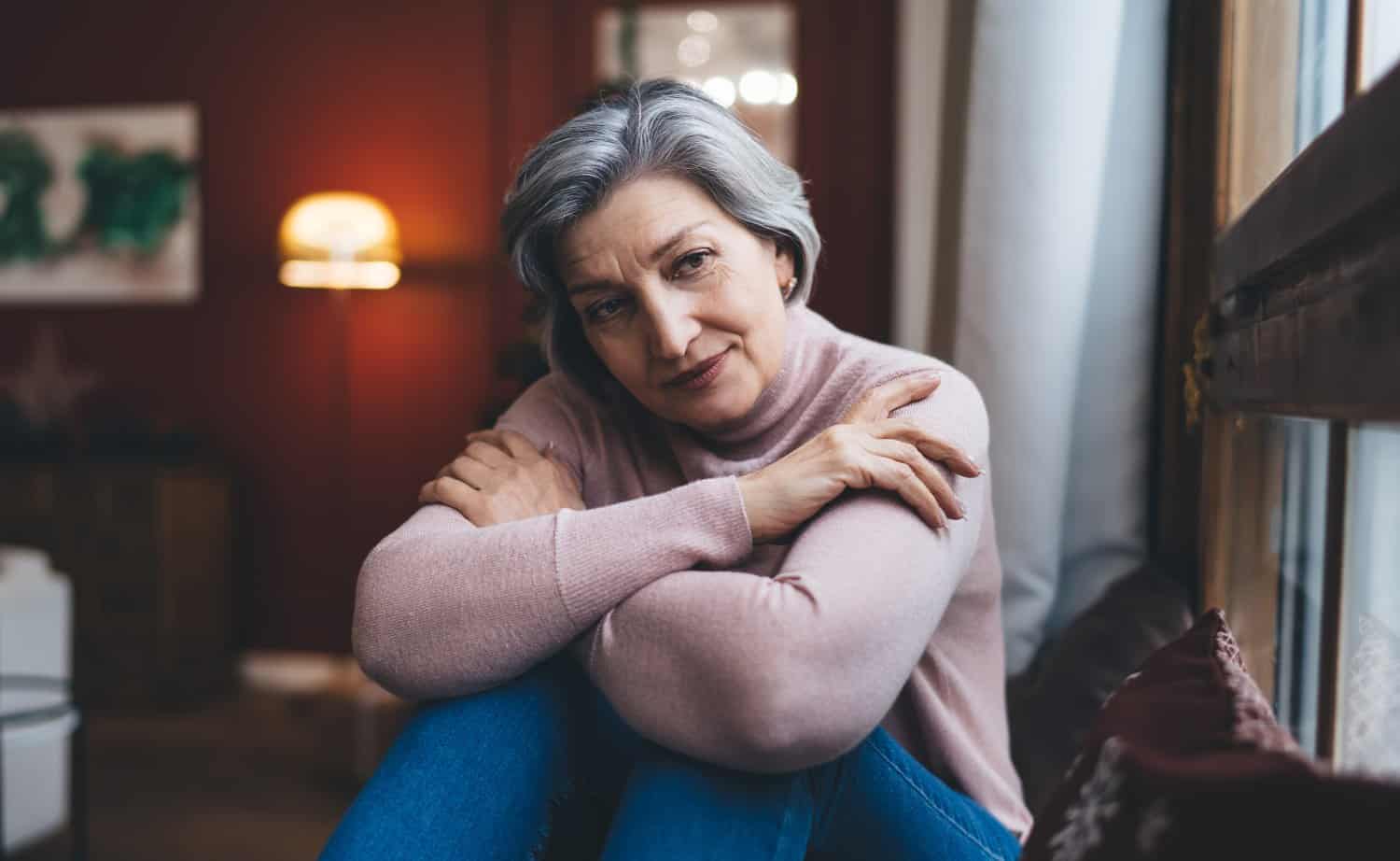 elderly woman sitting alone in the living room, concept of mental health and depression