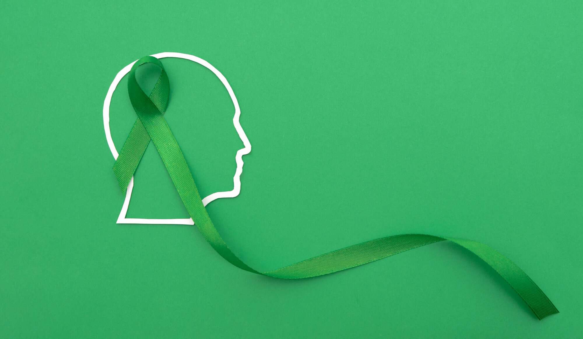 Profile outline of human head with a Green Ribbon on a Green Background, Mental Health Support concept